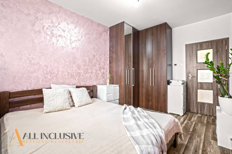 A bedroom with a bed, wardrobe, and wooden decor flooring in a three-room apartment.
