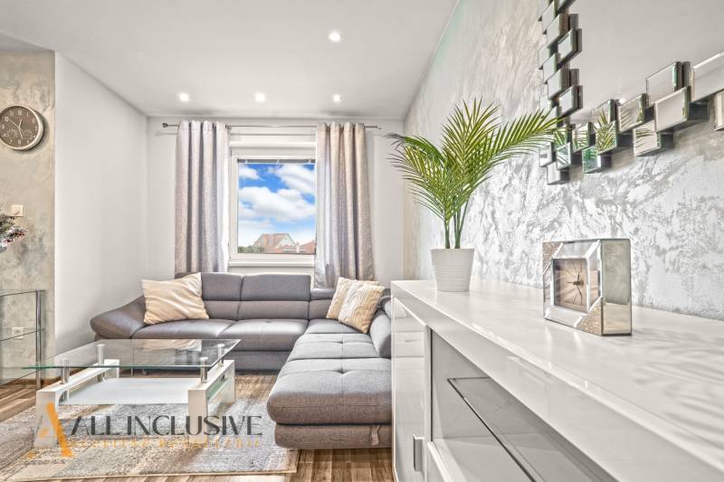 Living room with a gray sofa, glass table, and wood-patterned flooring.