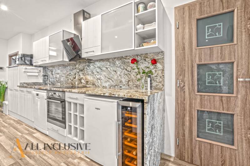 A kitchen in a 3-room apartment with a wooden decor floor and a marble countertop.