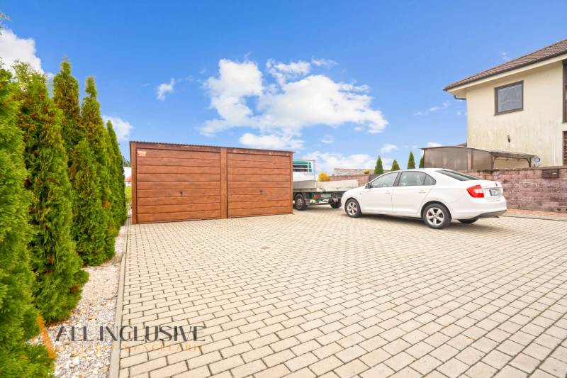Paved parking lot with a wooden garage and a car in Gabčíkovo near a 3-room apartment.