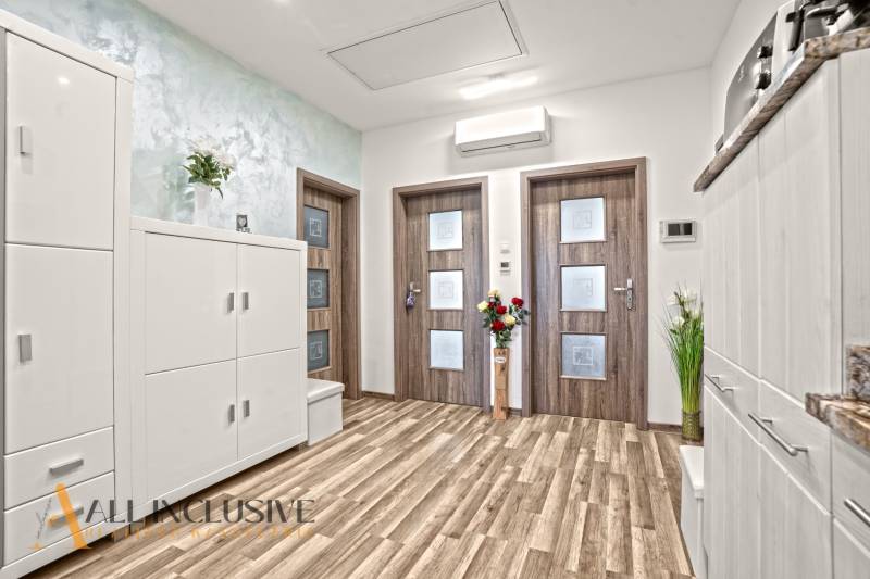 Interior of a 3-room apartment with a wood-patterned floor and white furniture.
