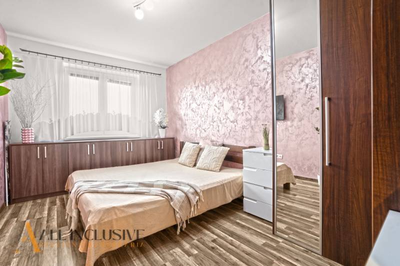 A bedroom with light walls, a wooden decor floor, and a comfortable bed in a 3-room apartment.