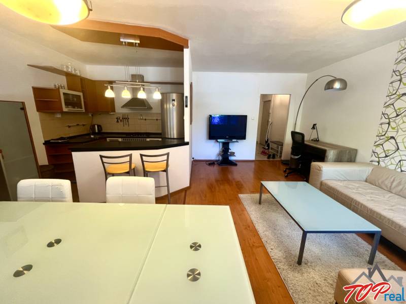Living room in a three-room apartment with a kitchen, dining table, and comfortable seating.