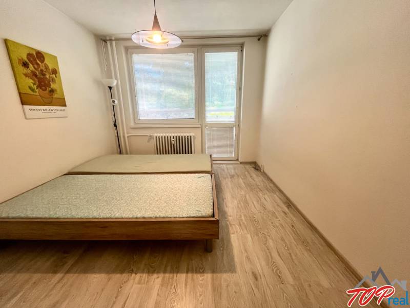 A bedroom with a light wooden bed and a painting in a 3-room apartment.