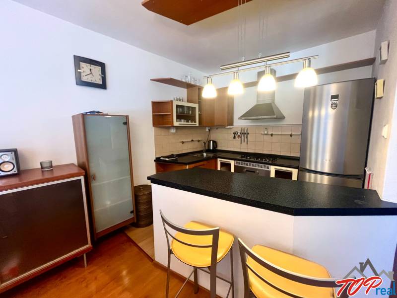 A kitchen in a 3-room apartment with a bar counter, metal chairs, and elegant lamps.
