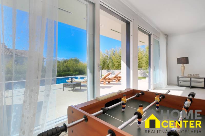 The interior of the villa with a view of the pool through glass doors, includes a foosball table.