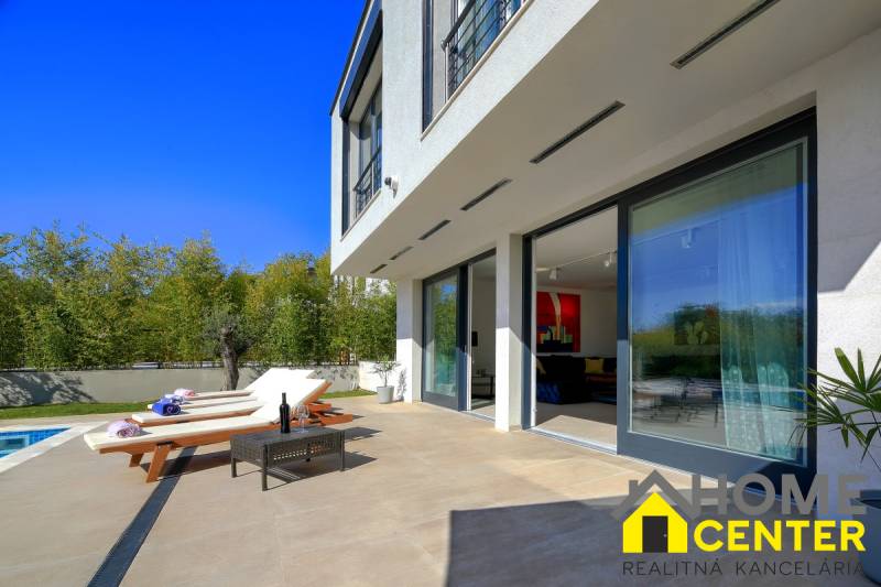 A villa in Bale with a terrace, loungers, a table, and a pool surrounded by greenery.