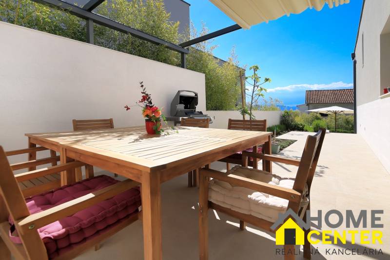 Terrace of the villa in Bale with wooden furniture, grill, and flowers, view of the countryside.