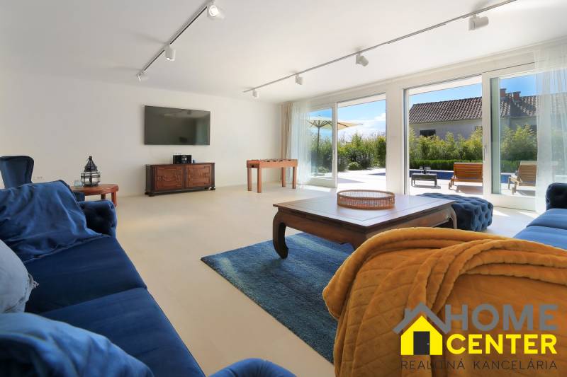 A living room in a villa with dark blue furniture, a TV, and large windows.