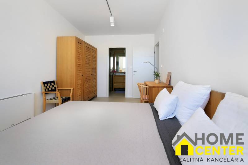 Bedroom in a villa with wooden furniture, a table, a chair, and a view into the bathroom.