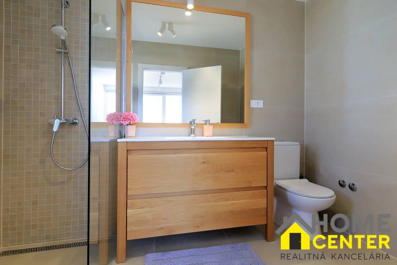 Bathroom in a villa with wooden decor, shower, and sink with a large mirror.
