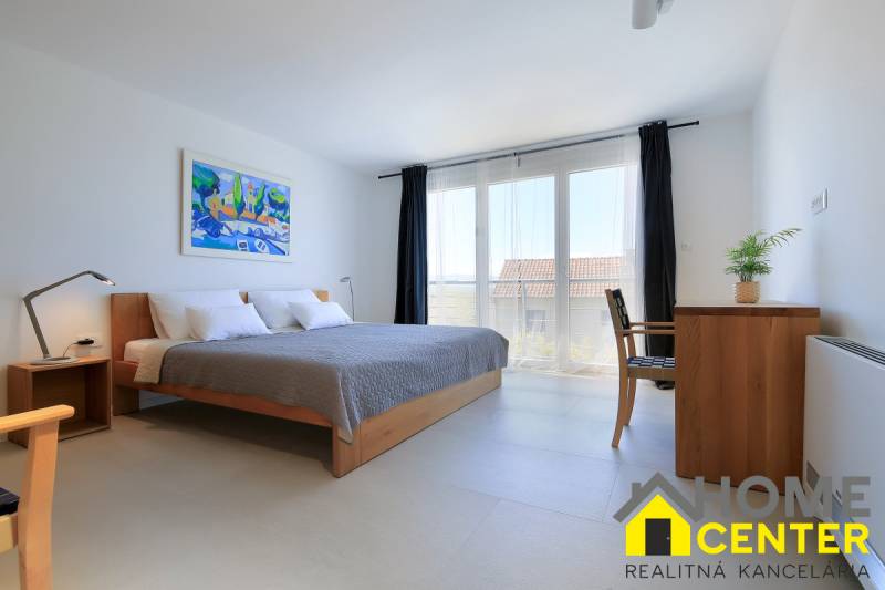 A bright bedroom with a large bed, a colorful painting, simple furniture in a villa.