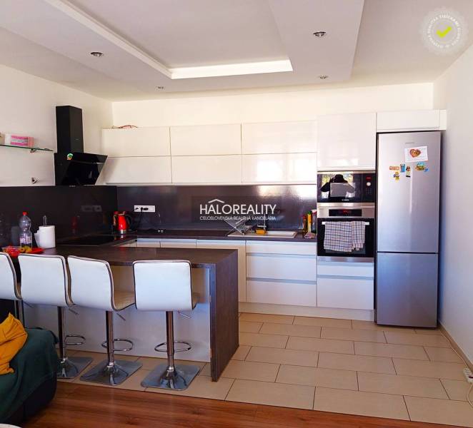 A kitchen in a 3-room apartment with a bar counter, white cabinets, and modern appliances.