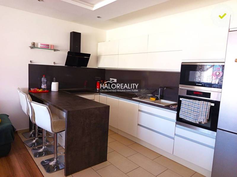 A kitchen with white cabinets and a bar counter in a 3-room apartment.
