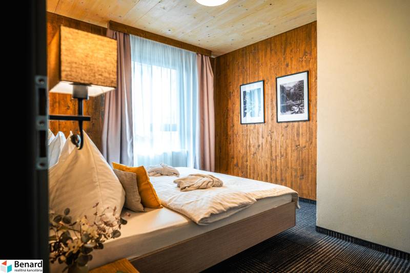 Bedroom in a 2-room apartment with wooden paneling, carpet, and two paintings on the wall.