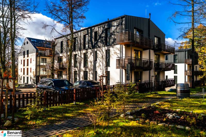 The exterior of the apartment building on Lúčná Street in Štrba with parked vehicles and a landscaped surroundings.