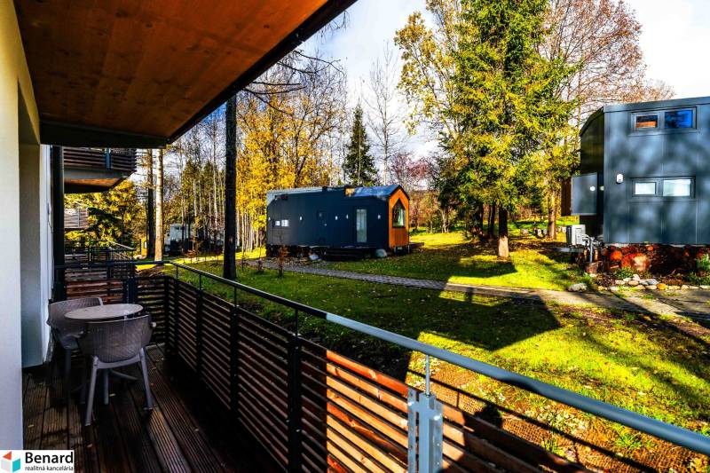 The balcony of a 2-room apartment on Lúčná in Štrba with a view of the garden with trees.