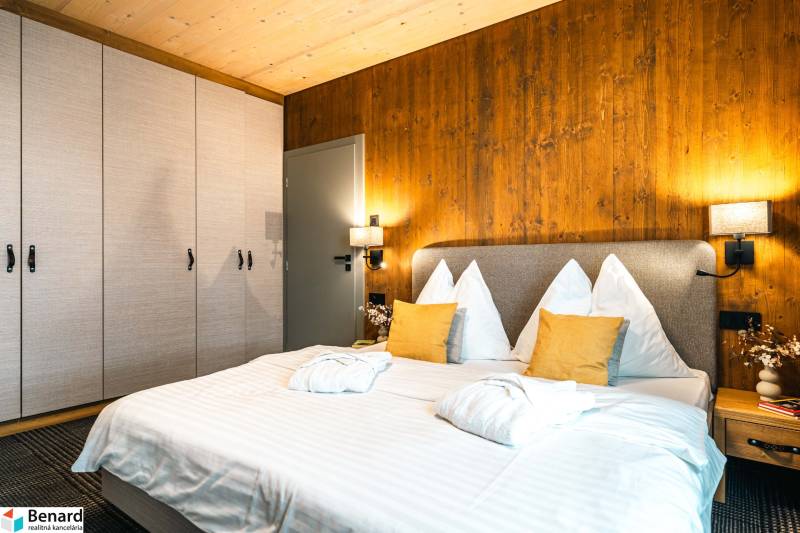 Bedroom in a 2-room apartment with a bed, wardrobe, and wall with wooden decor.