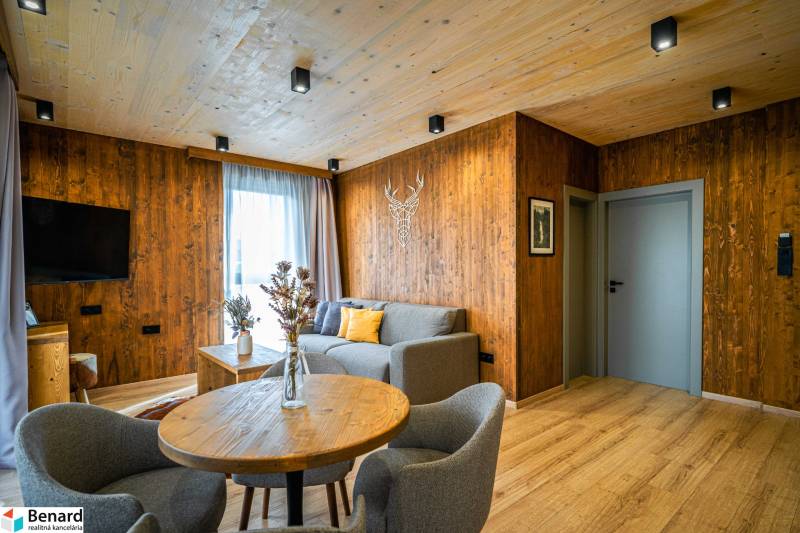 Living room in a 2-room apartment with a wood-patterned floor and wooden paneling.