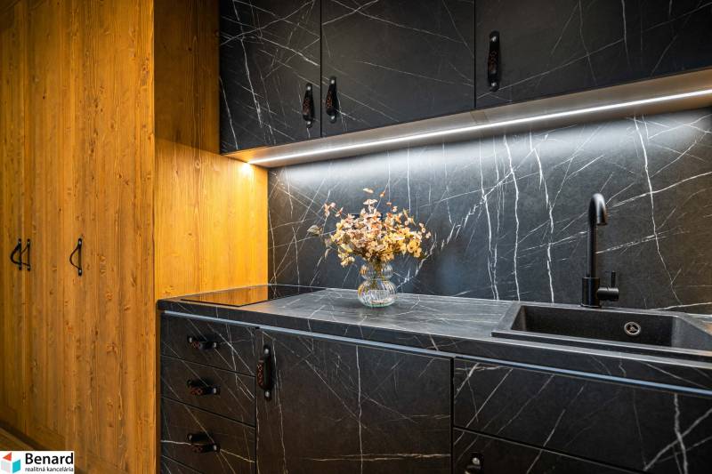 A kitchen unit in a 2-room apartment with a marble effect and a wooden cabinet.