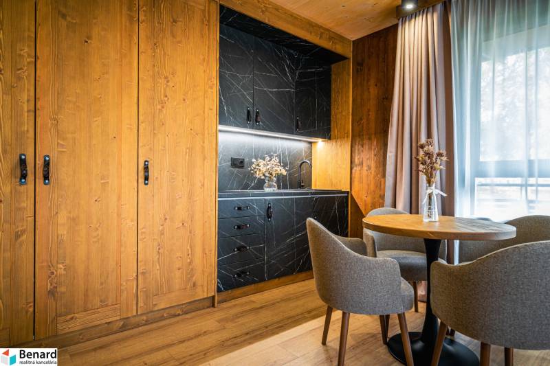 A kitchen corner with black marble decor and a floor with wooden decor in a 2-room apartment.