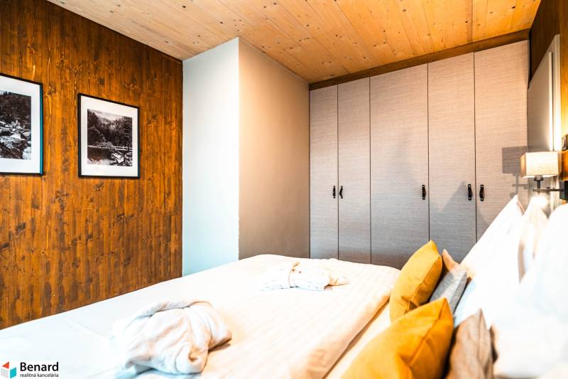 Bedroom in a 2-room apartment with a bed, wardrobe, and pictures on wooden paneling.