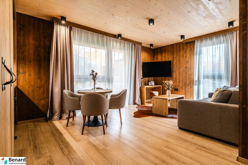 Living room in a two-room apartment with a wooden decor floor, a sofa, and a dining table.