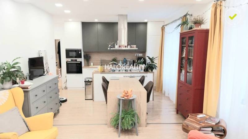 A kitchen in a 3-room apartment with a wooden decor floor, a dining table, and a bookshelf.