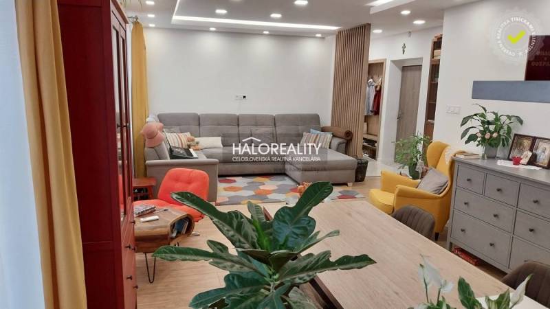 Living room in a 3-room apartment with seating, flowers, and a wooden decor floor.