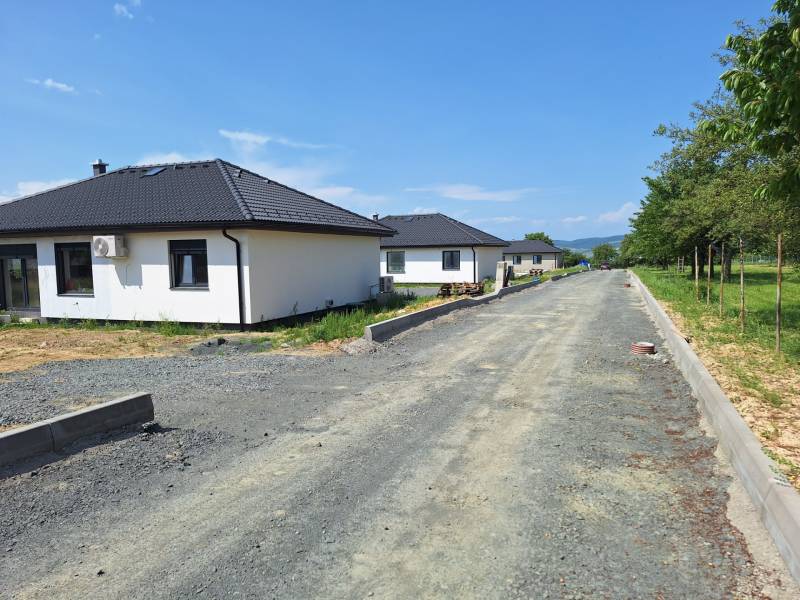 Family houses on Vyšná Šebastová Street in Prešov surrounded by greenery, next to an unfinished road.
