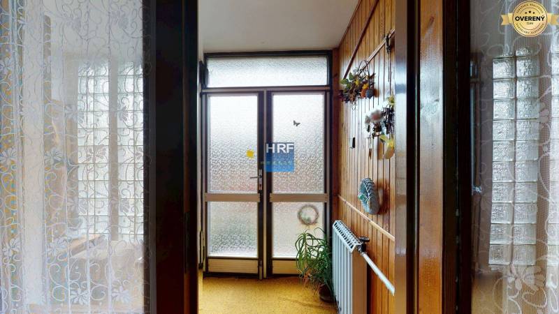 A hallway in a family house with wooden decor, glass doors, and a houseplant.