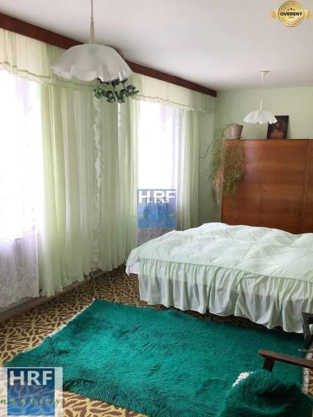 A bedroom in a family house with carpets, curtains, and a wooden wardrobe.