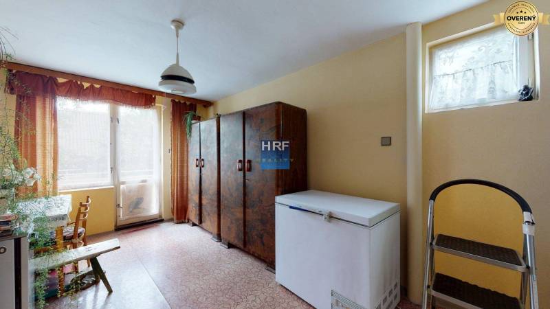 Interior of a family house with a freezer, cabinets, and a large window.