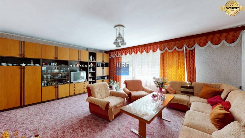 Living room in a family house with a sofa set, a living room wall unit, and flowers.