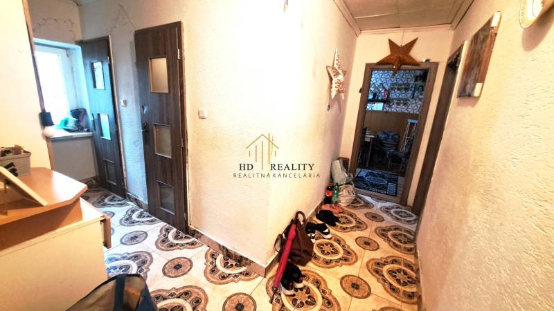 A hallway in a 2-room apartment with decorative tiles and furniture.