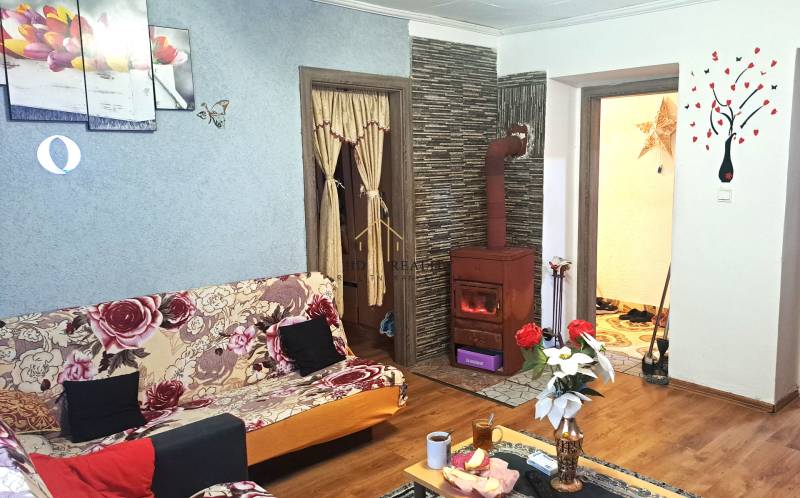 Living room in a two-room apartment with a tiled stove and a wooden decor floor.