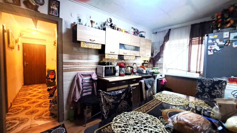 A kitchen in a 2-room apartment with a light wooden decor floor and rich furnishings.
