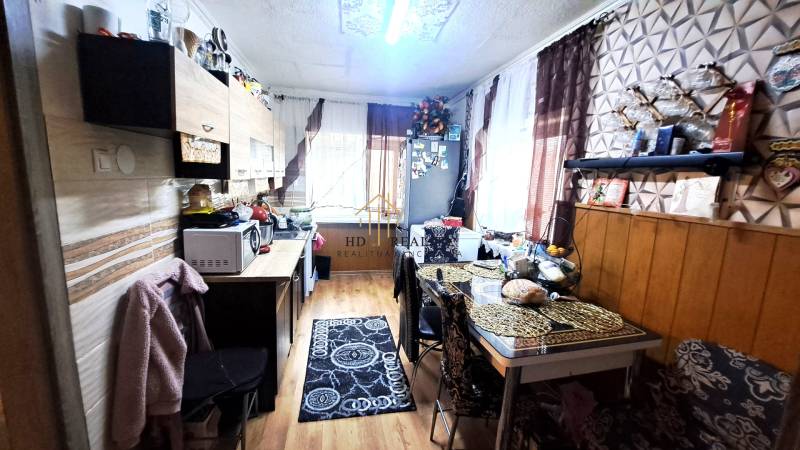 A kitchen in a 2-room apartment with a wooden decor floor and a dining table.