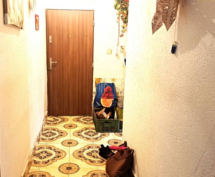 A hallway in a 2-room apartment with decorative tiles and doors with a wood decor.