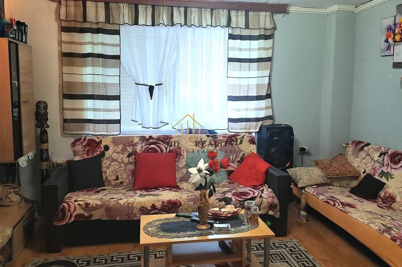 Living room in a two-room apartment with patterned sofas and a wooden decor floor.