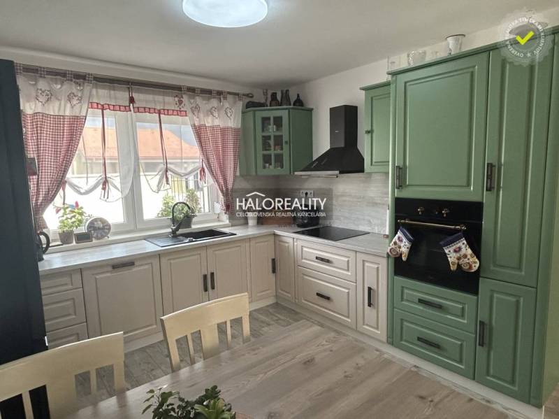 A kitchen in a family house with wooden furniture and curtains.