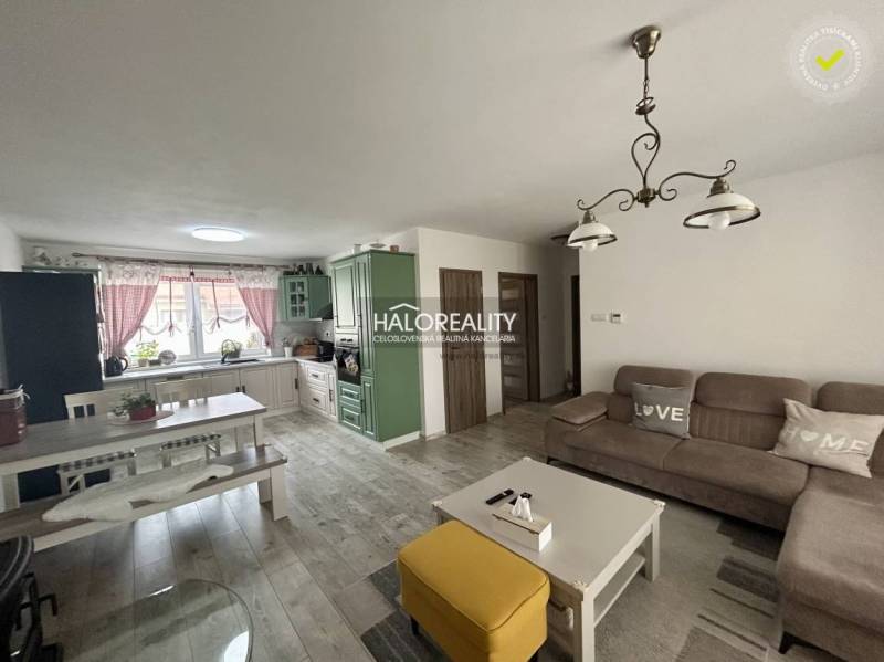 Living room in a family house with a sofa set, table, and kitchen unit.