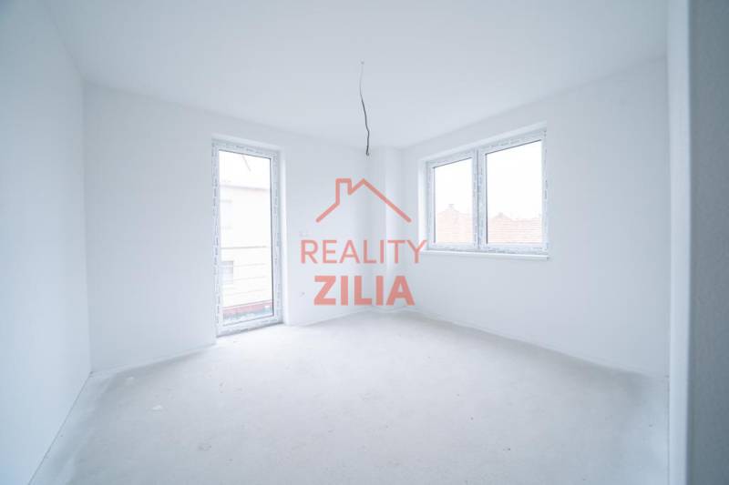 An empty room in a family house with white walls and large windows.