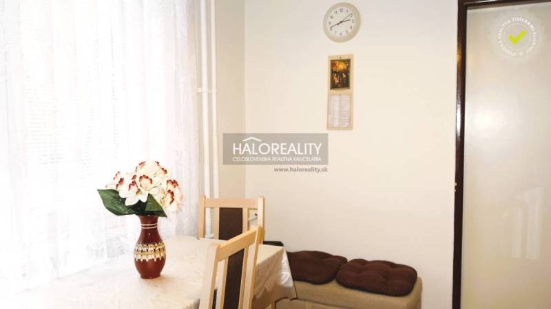 Dining area in a 3-room apartment with a flower on the table and a white curtain.