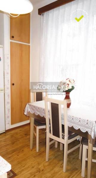 Dining room in a three-room apartment with a wood-patterned floor and light curtains.