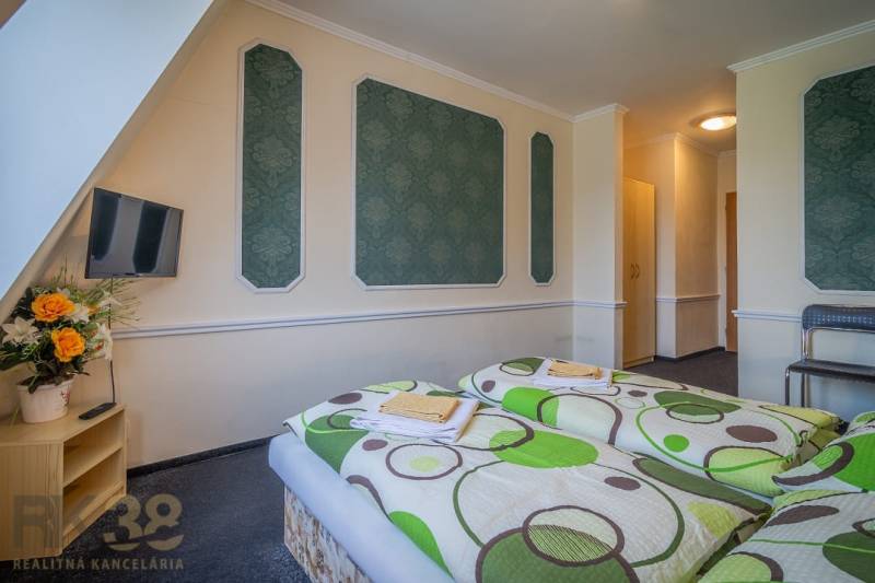 A room in hotels and guesthouses with two beds, a television, and flowers on the table.