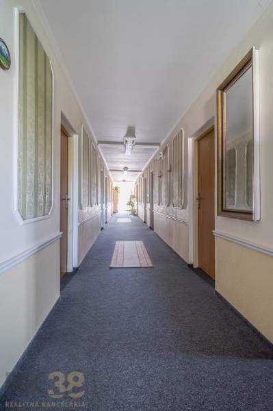 A long corridor with doors, carpets, and mirrors in a hotel or guesthouse.