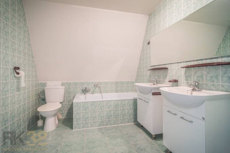 A bathroom with a bathtub, two sinks, and green tiles in hotels and guesthouses.