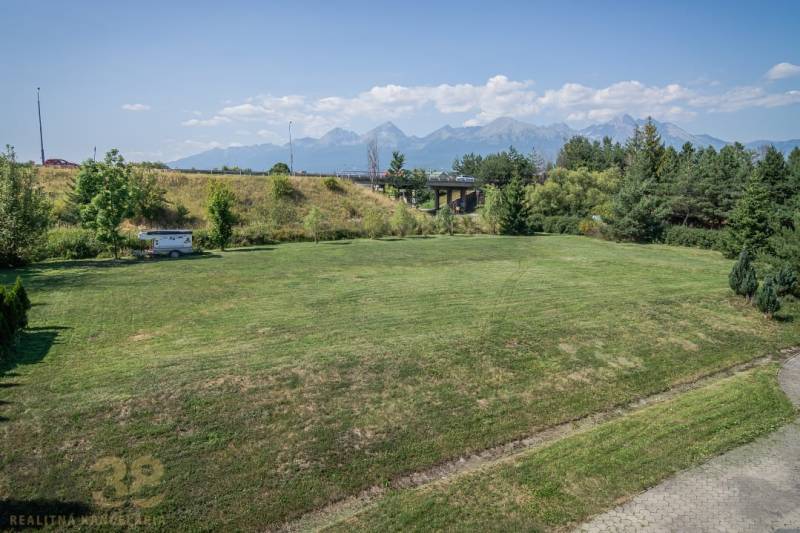 A view of a grassy area with a view of the Tatras, Poprad, hotels, and guesthouses.
