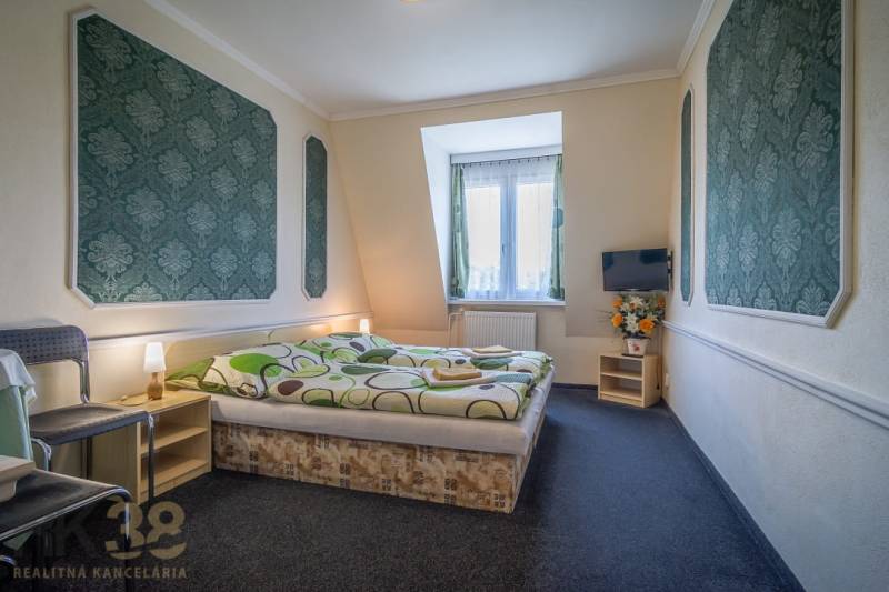 A room with a double bed, carpeted floor, television, chair, and decorations in hotels and guesthouses.